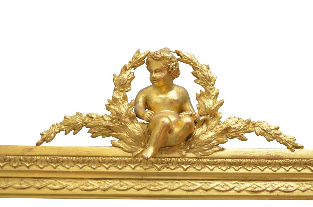 An ornate antique giltwood mantel mirror featuring a carved cherub crest and classical detailing. View IX
