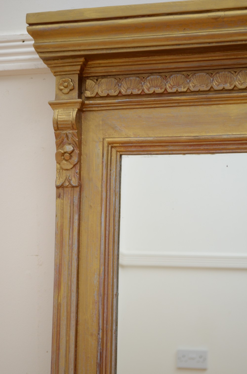 An upright Edwardian wall mirror featuring a carved wooden frame with gilt finish and decorative fluted pilasters. View V