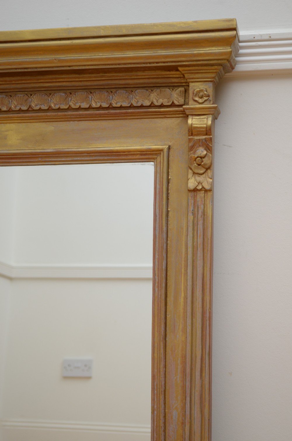 An upright Edwardian wall mirror featuring a carved wooden frame with gilt finish and decorative fluted pilasters. View X