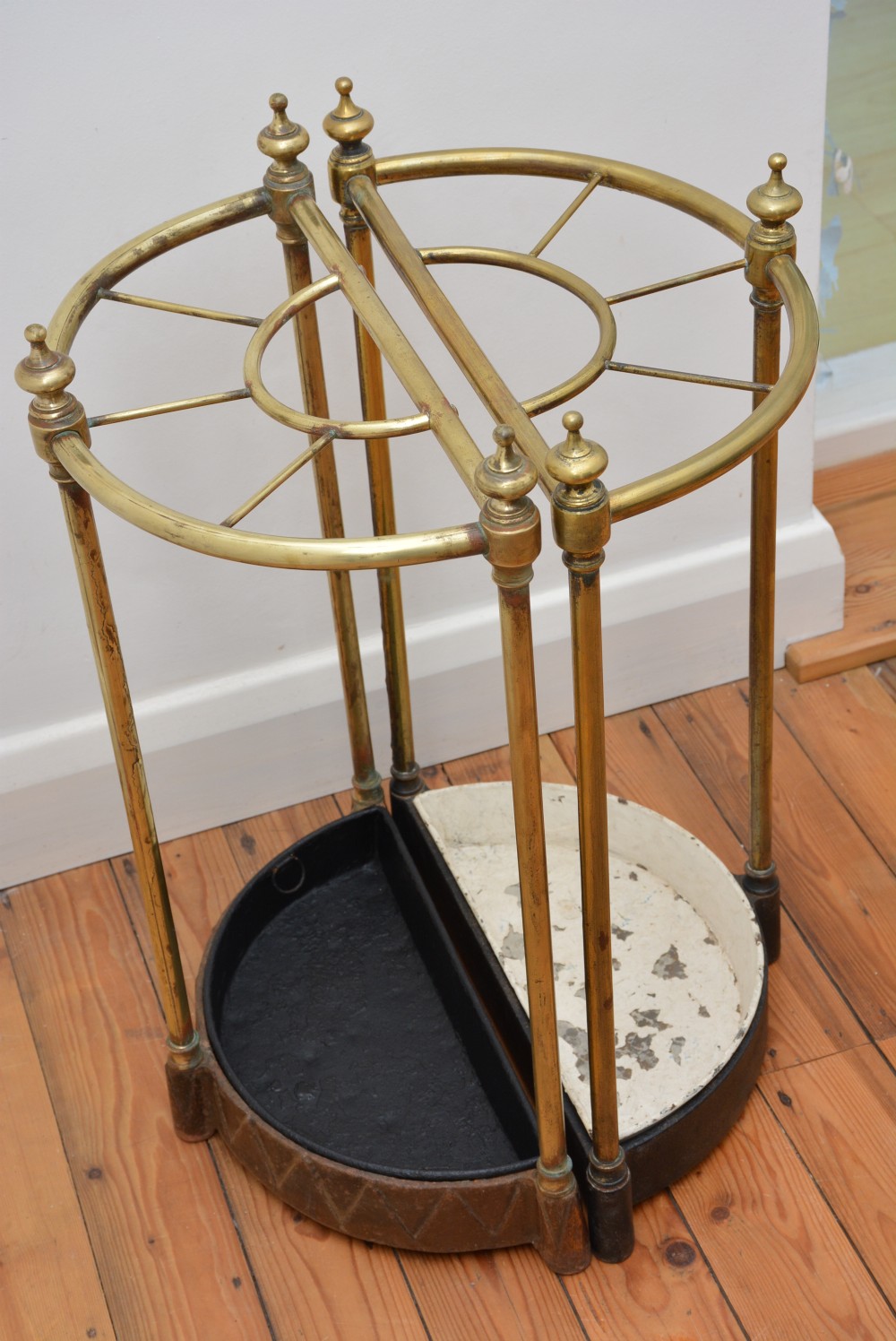 A pair of semi-circular Victorian brass umbrella stands featuring turned finials, internal division rails, and heavy black cast iron drip bases. View VIII