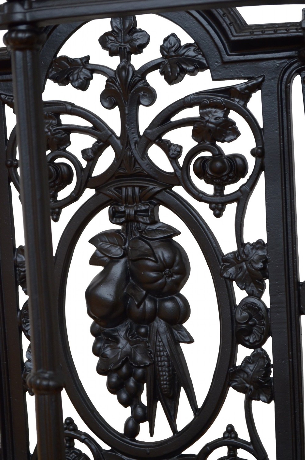 A Victorian black cast iron umbrella stand featuring an ornate foliage backplate, top railing, finials, and a removable drip tray base. View V