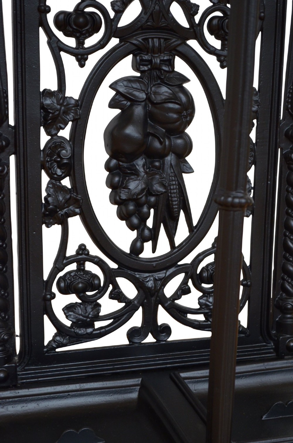 A Victorian black cast iron umbrella stand featuring an ornate foliage backplate, top railing, finials, and a removable drip tray base. View VI