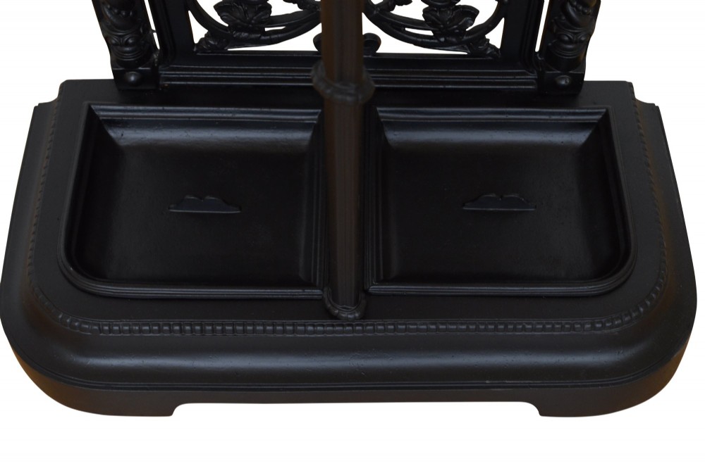 A Victorian black cast iron umbrella stand featuring an ornate foliage backplate, top railing, finials, and a removable drip tray base. View VII