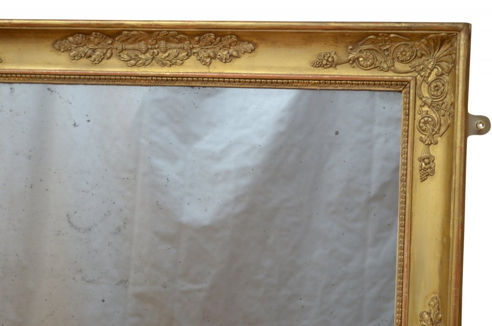 A rectangular Napoleonic giltwood wall mirror featuring detailed foliate low-relief carvings along the gilded frame. View V