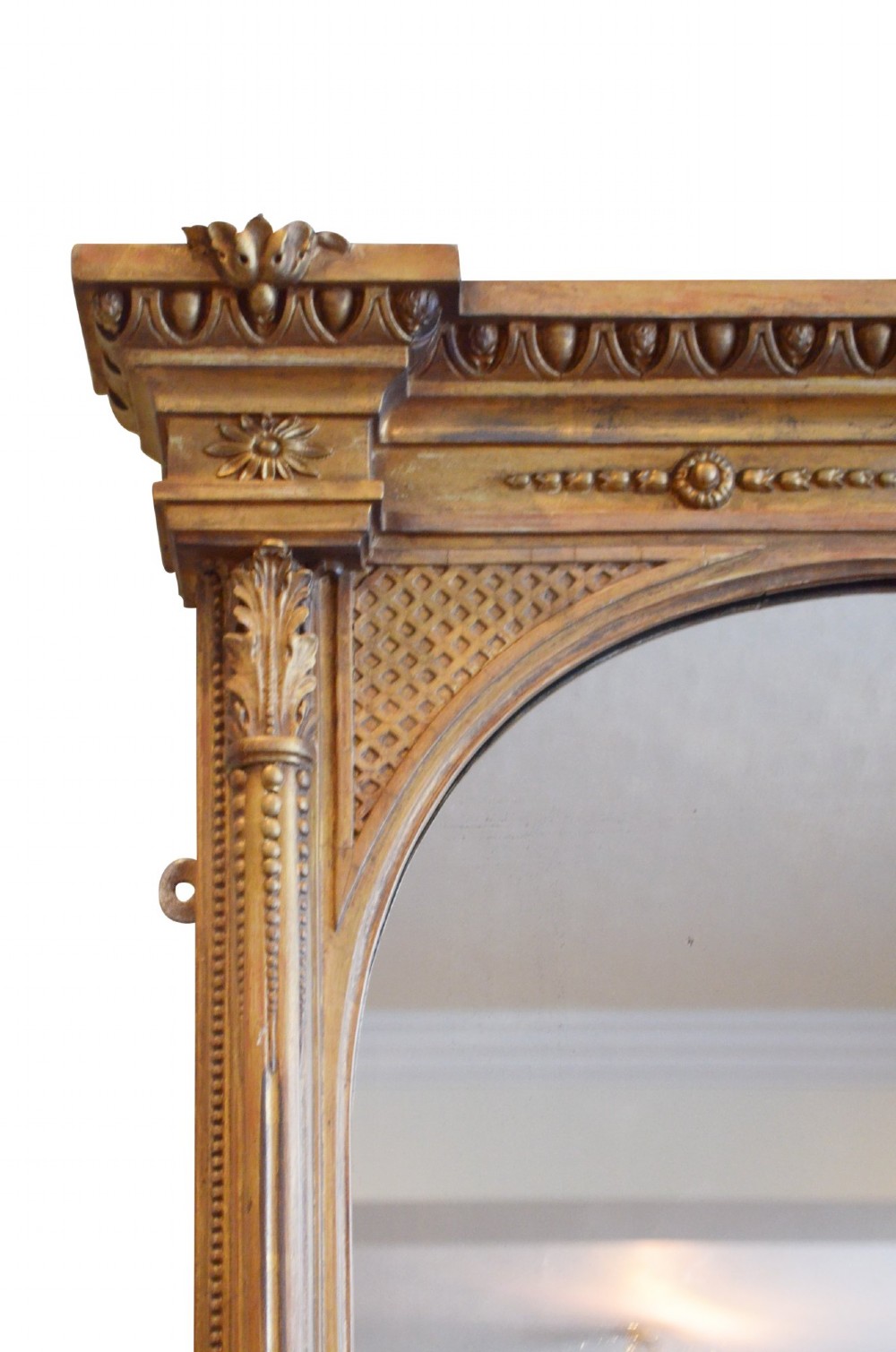 A large rectangular giltwood overmantel mirror featuring an arched top frame, carved cresting, side pilasters, and a gold finish. View IX