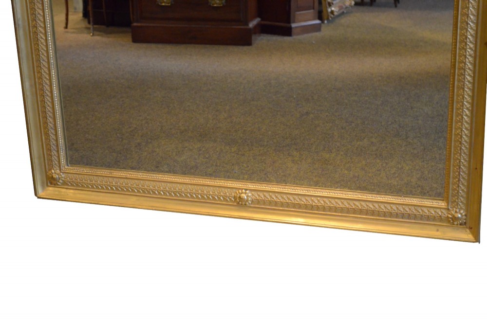 A large rectangular antique wall mirror featuring a carved giltwood frame decorated with detailed classical bead moulding and rosette bosses. View II