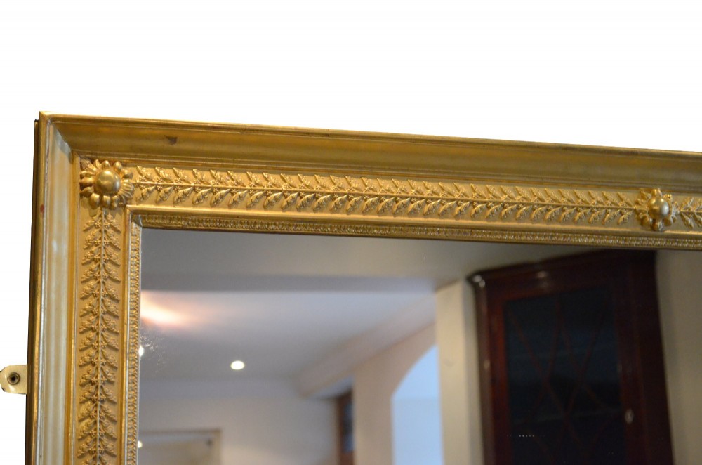 A large rectangular antique wall mirror featuring a carved giltwood frame decorated with detailed classical bead moulding and rosette bosses. View VIII