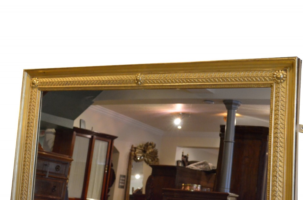 A large rectangular antique wall mirror featuring a carved giltwood frame decorated with detailed classical bead moulding and rosette bosses. View IX