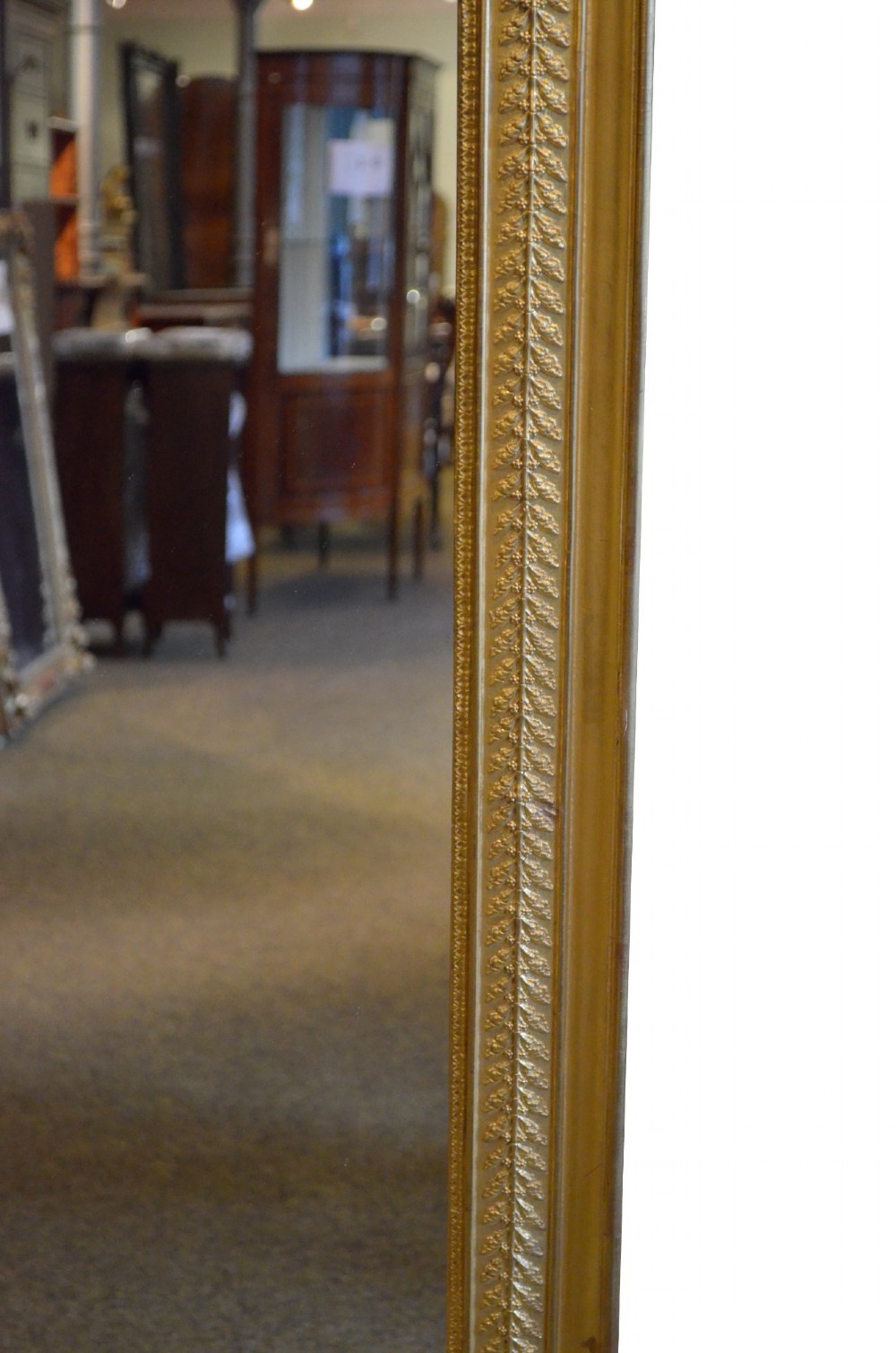 A large rectangular antique wall mirror featuring a carved giltwood frame decorated with detailed classical bead moulding and rosette bosses. View X