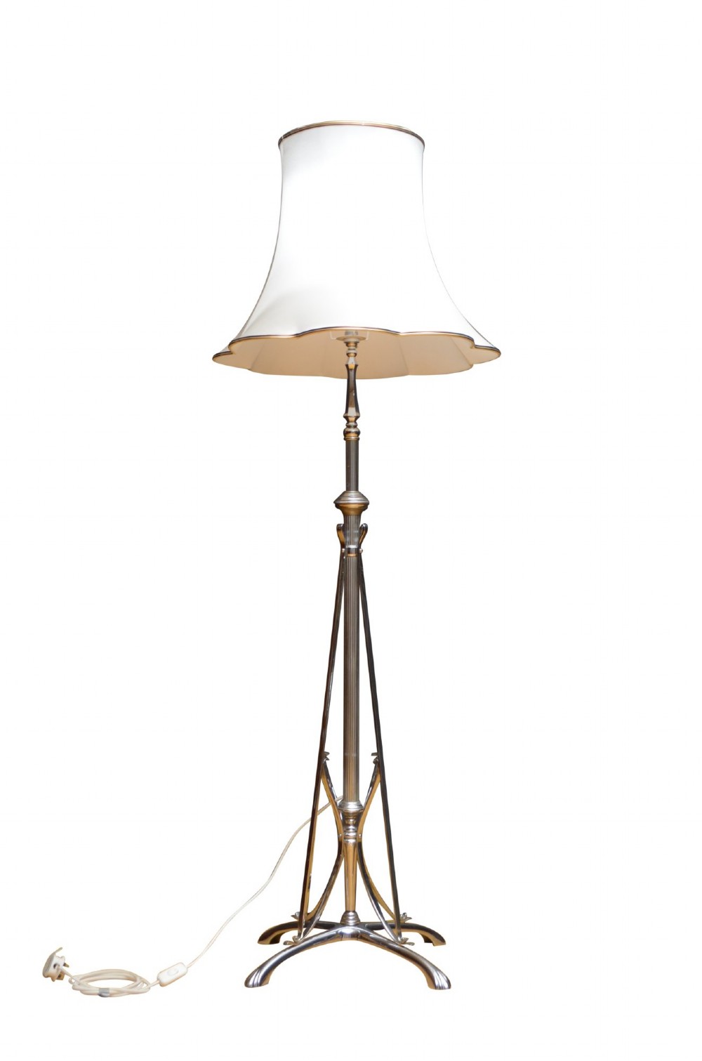 An Art Deco metal standard lamp featuring a fluted central stem, tripod sweeping base supports, and a scalloped white fabric shade.