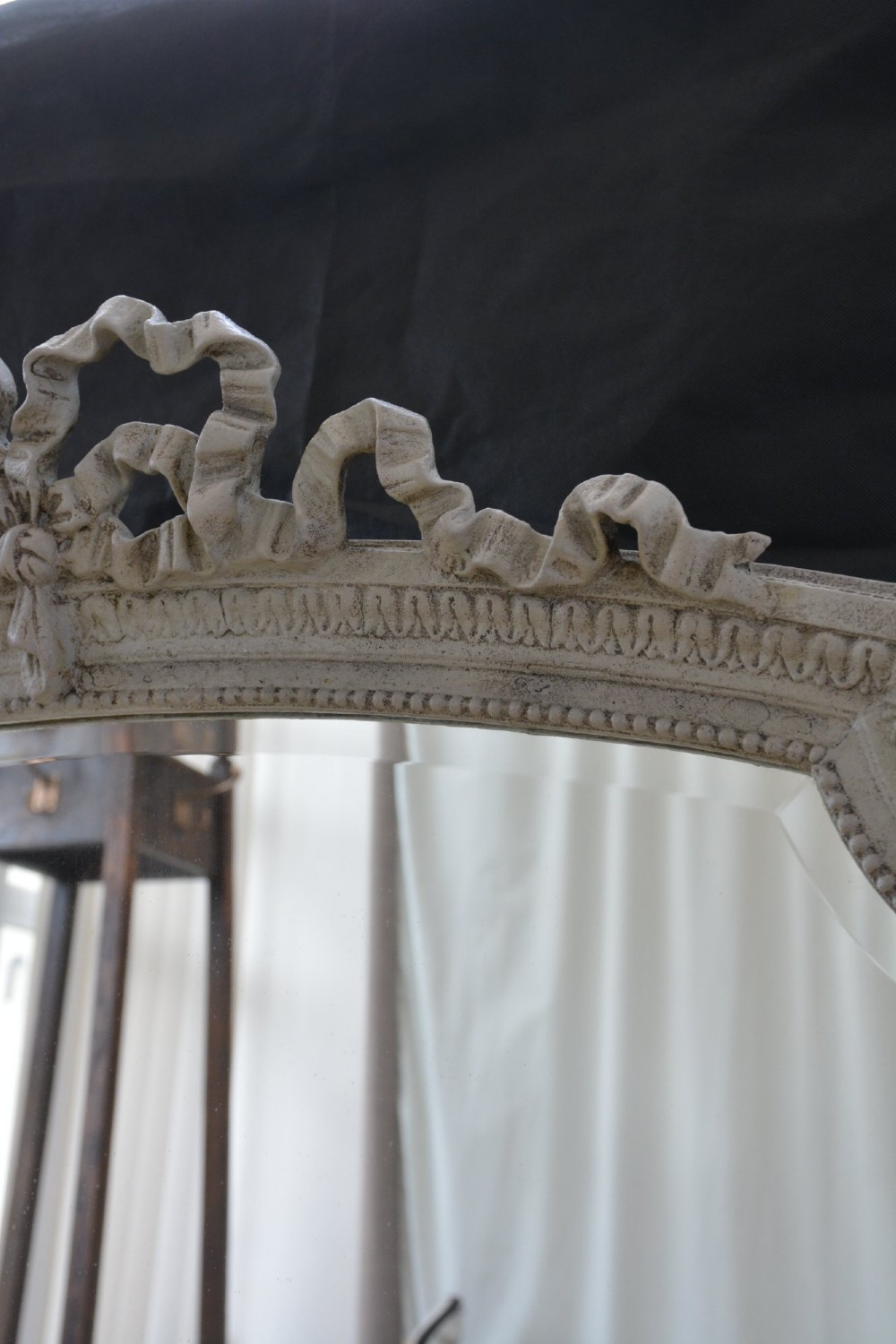 A tall grey-painted French Rococo style wall mirror featuring a carved ribbon top crest and scroll detailing. View II