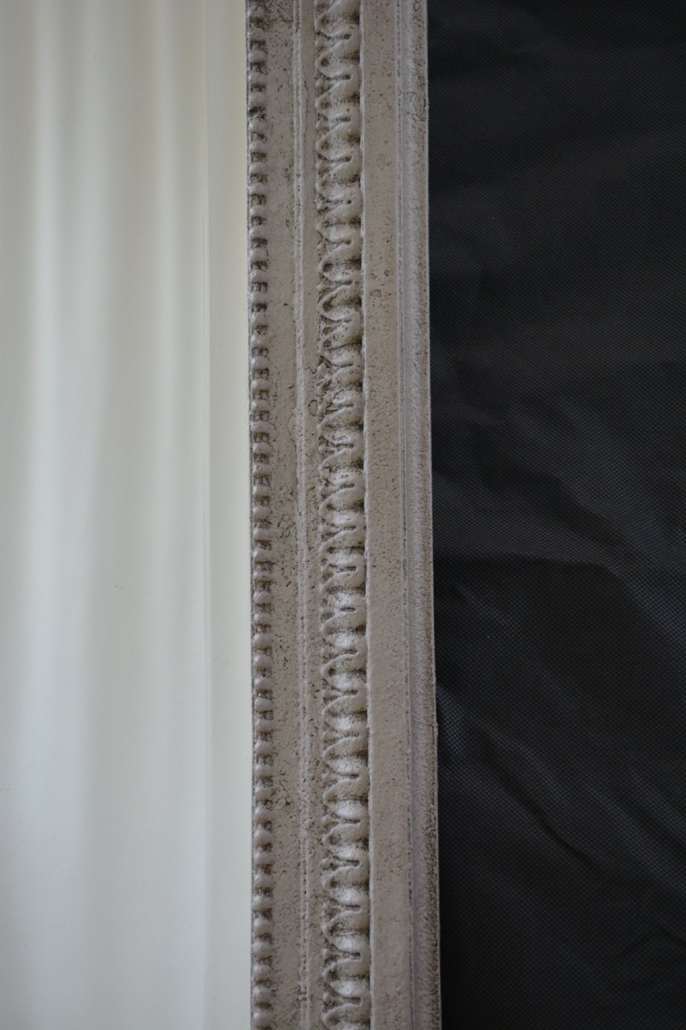 A tall grey-painted French Rococo style wall mirror featuring a carved ribbon top crest and scroll detailing. View IV