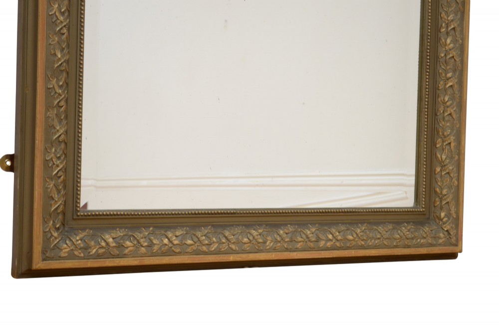 A tall antique French pier mirror featuring a gilded ribbon cresting, carved floral swags, and leaf moulding framing rectangular mirror glass. View X