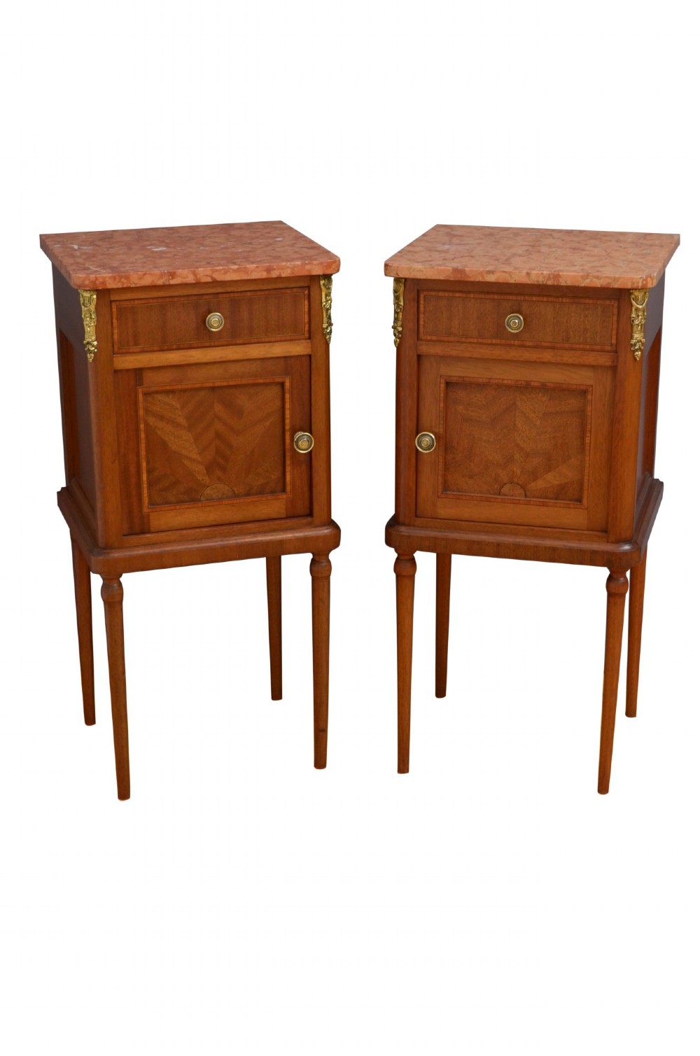A pair of tall French Louis XVI style wooden bedside cabinets featuring pink marble tops, single drawers, cupboard doors with sunburst parquetry motifs, and slender turned legs. View VIII