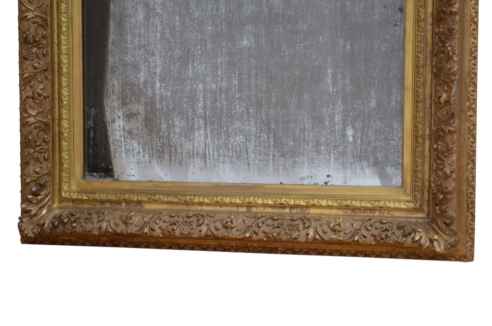 A rectangular antique Rococo giltwood wall mirror featuring carved acanthus foliage mouldings around a heavily foxed mirror glass pane. View VII