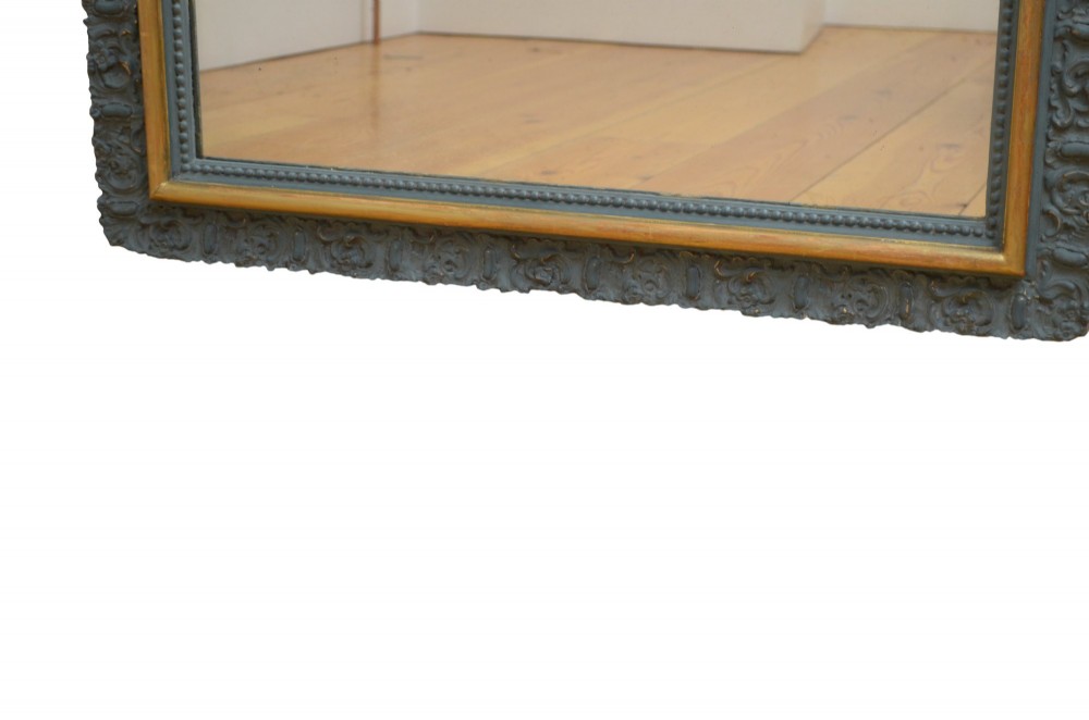A tall rectangular wall mirror featuring a dark grey carved frame with a golden inner bead and an intricate foliage crest at the top. View V