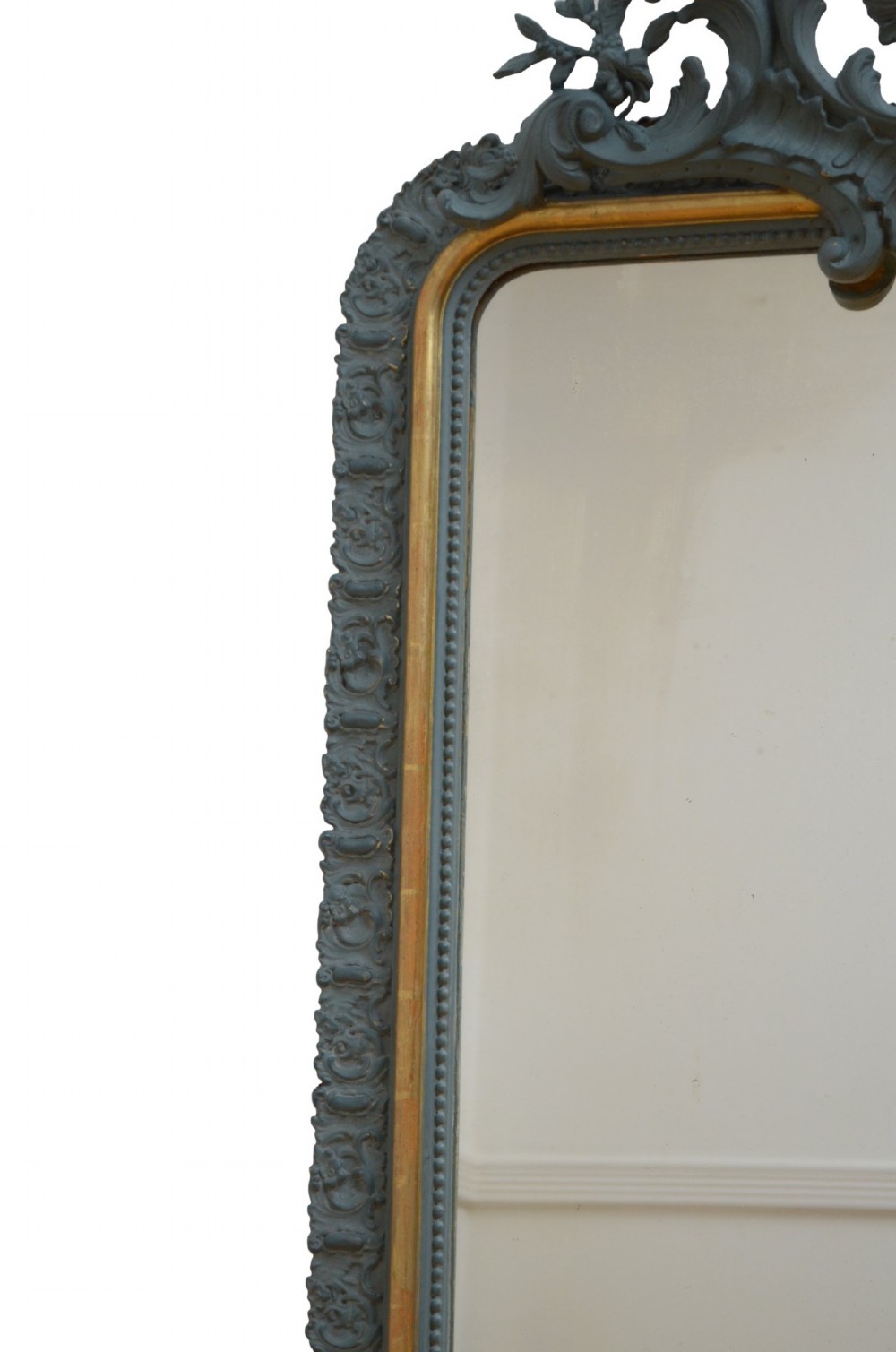 A tall rectangular wall mirror featuring a dark grey carved frame with a golden inner bead and an intricate foliage crest at the top. View VII