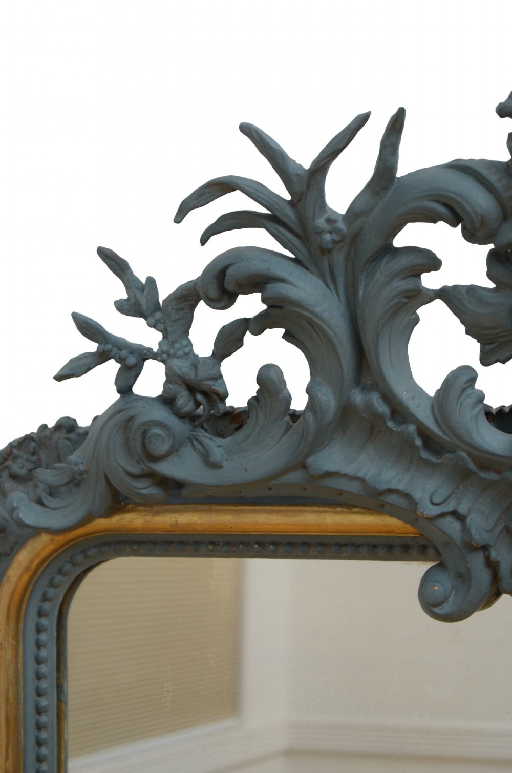 A tall rectangular wall mirror featuring a dark grey carved frame with a golden inner bead and an intricate foliage crest at the top. View X