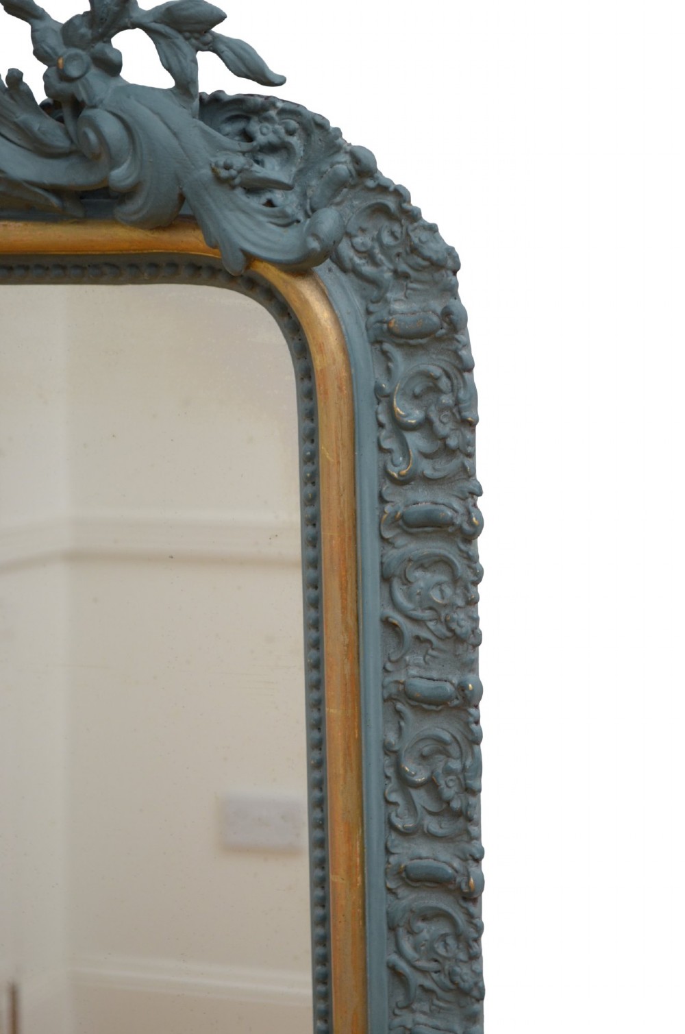 A tall rectangular wall mirror featuring a dark grey carved frame with a golden inner bead and an intricate foliage crest at the top. View XIII