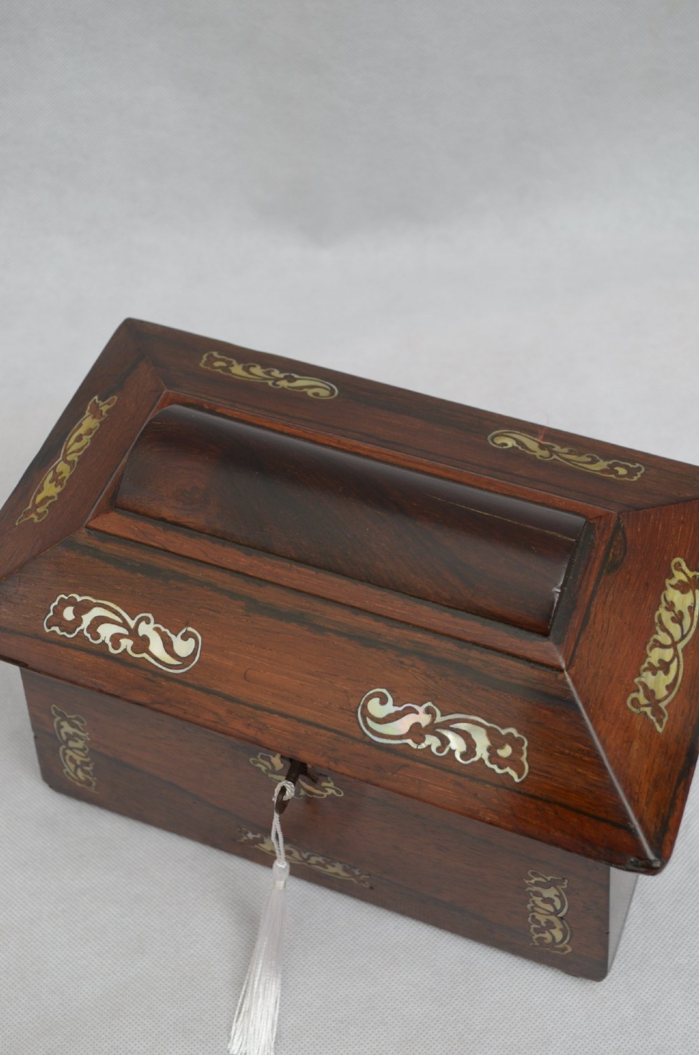 A Regency period rosewood tea caddy in a sarcophagus shape with mother-of-pearl floral scroll inlay and a brass keyhole. View III