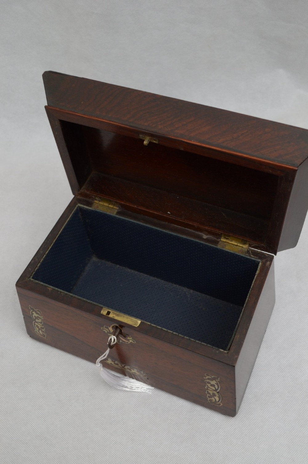 A Regency period rosewood tea caddy in a sarcophagus shape with mother-of-pearl floral scroll inlay and a brass keyhole. View V