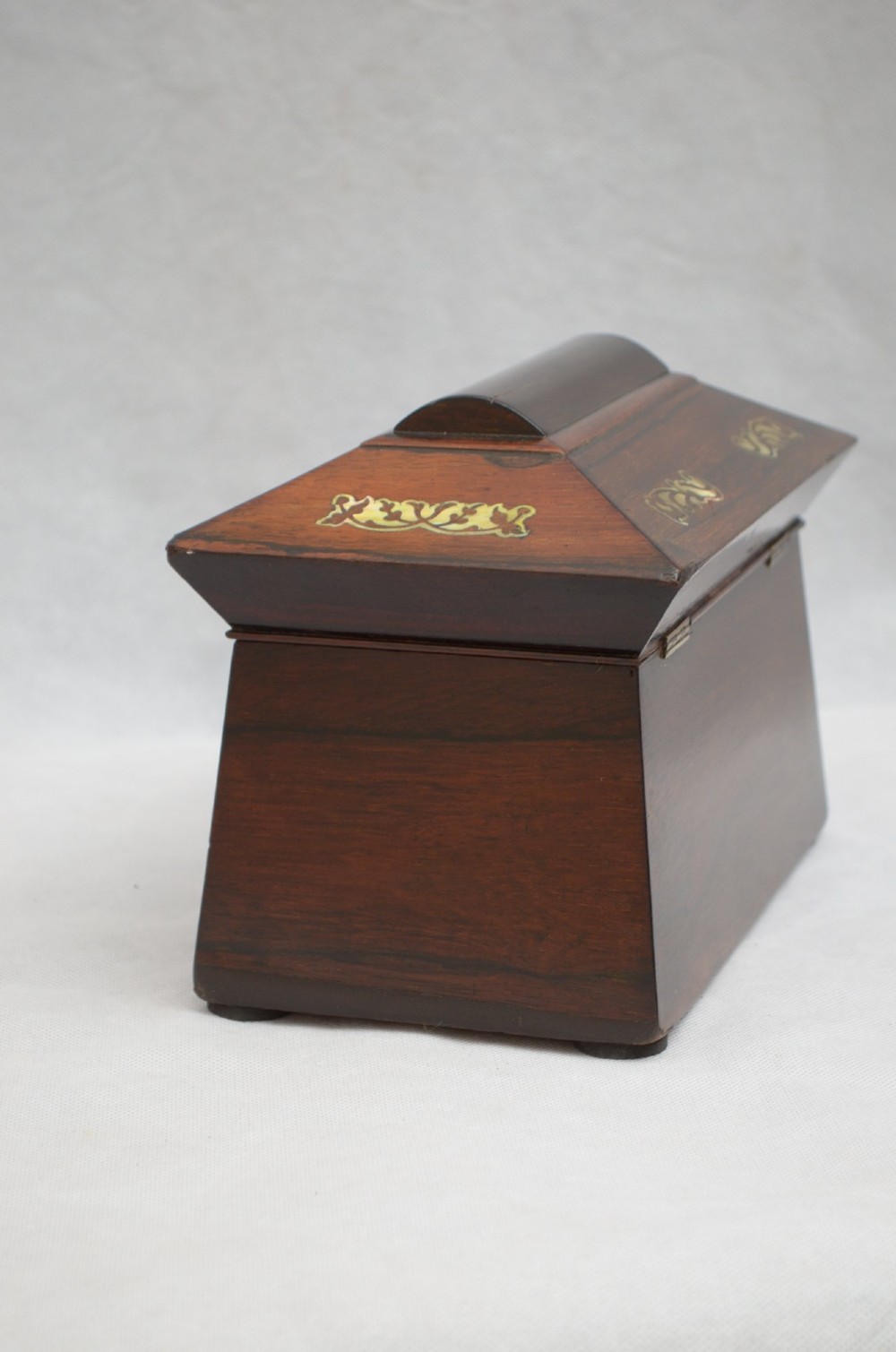 A Regency period rosewood tea caddy in a sarcophagus shape with mother-of-pearl floral scroll inlay and a brass keyhole. View VI