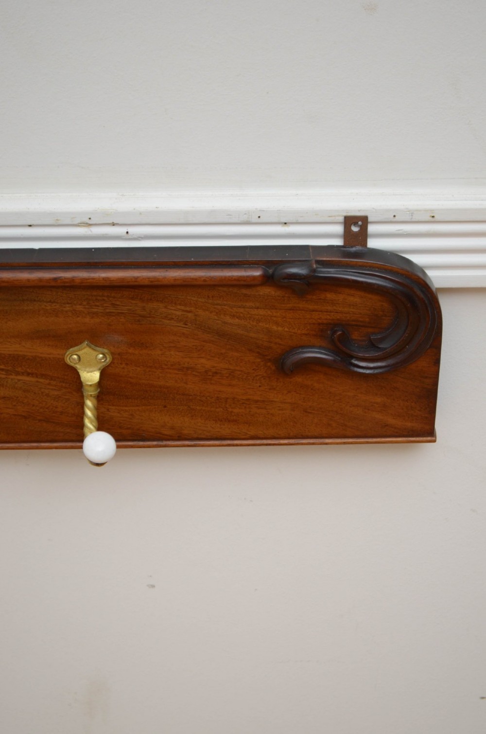 An antique wall-mounted mahogany coat rack featuring five rope-twist brass hooks topped with white ceramic knobs and carved scrollwork details. View XI