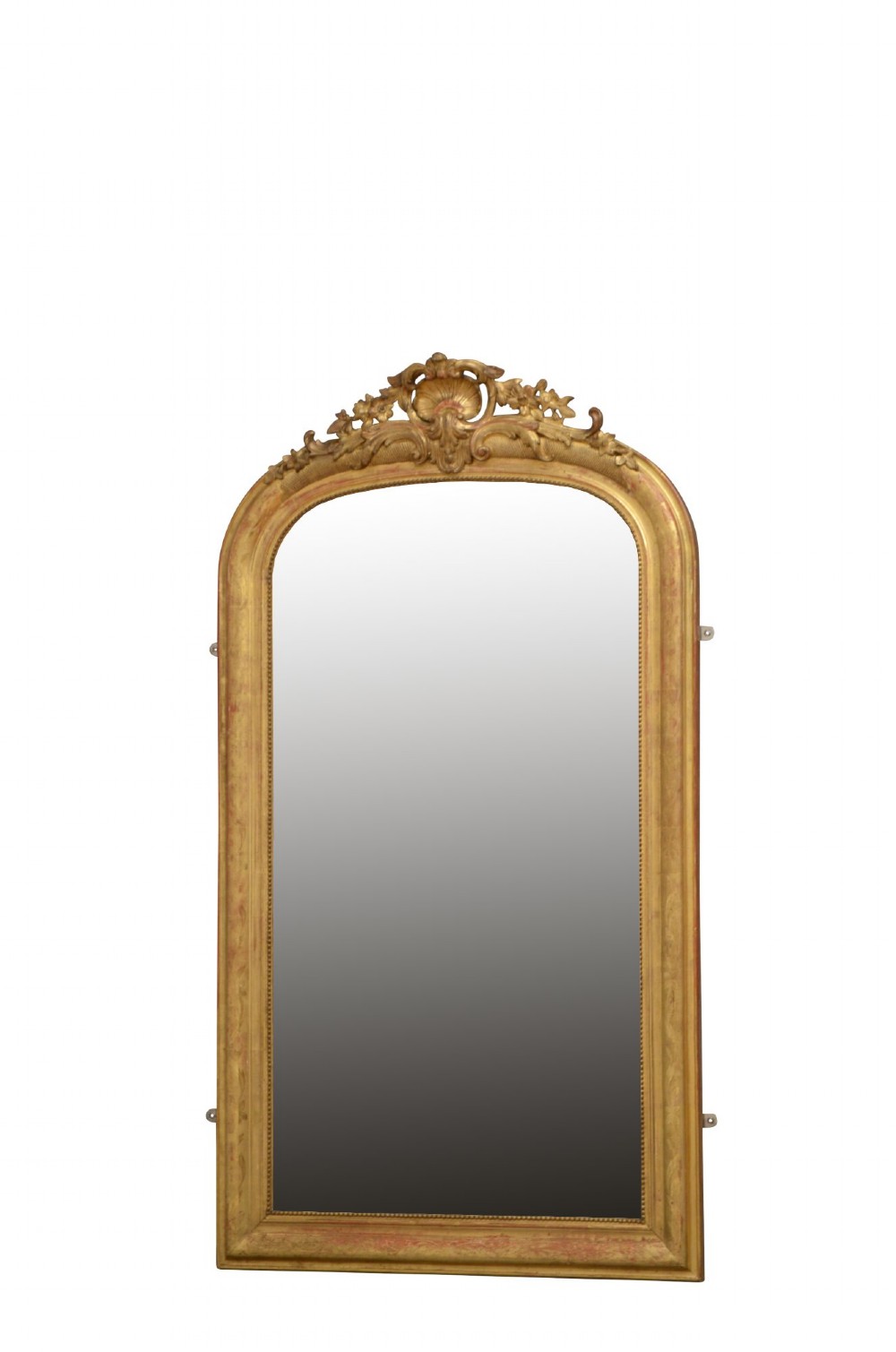 A tall arched giltwood wall mirror featuring an intricate shell cresting at the top and floral carved motifs along the gilded frame.