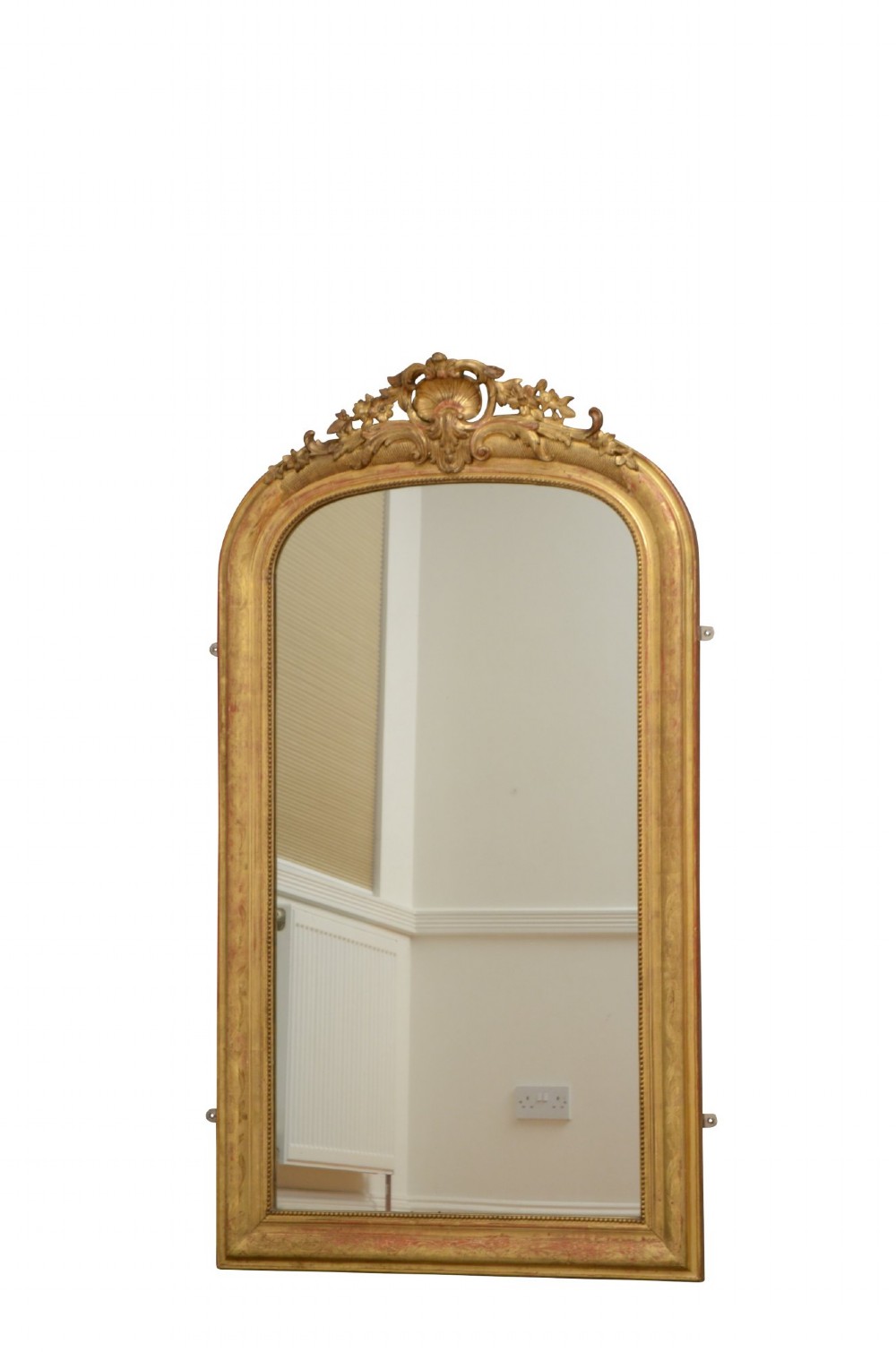 A tall arched giltwood wall mirror featuring an intricate shell cresting at the top and floral carved motifs along the gilded frame. View III