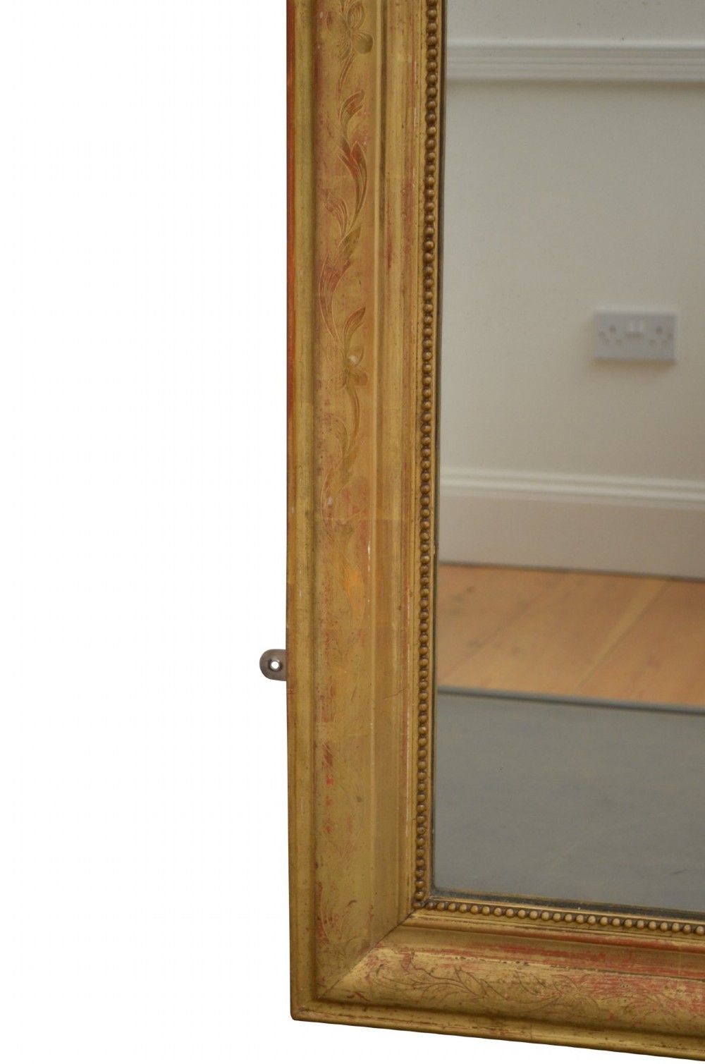 A tall arched giltwood wall mirror featuring an intricate shell cresting at the top and floral carved motifs along the gilded frame. View V