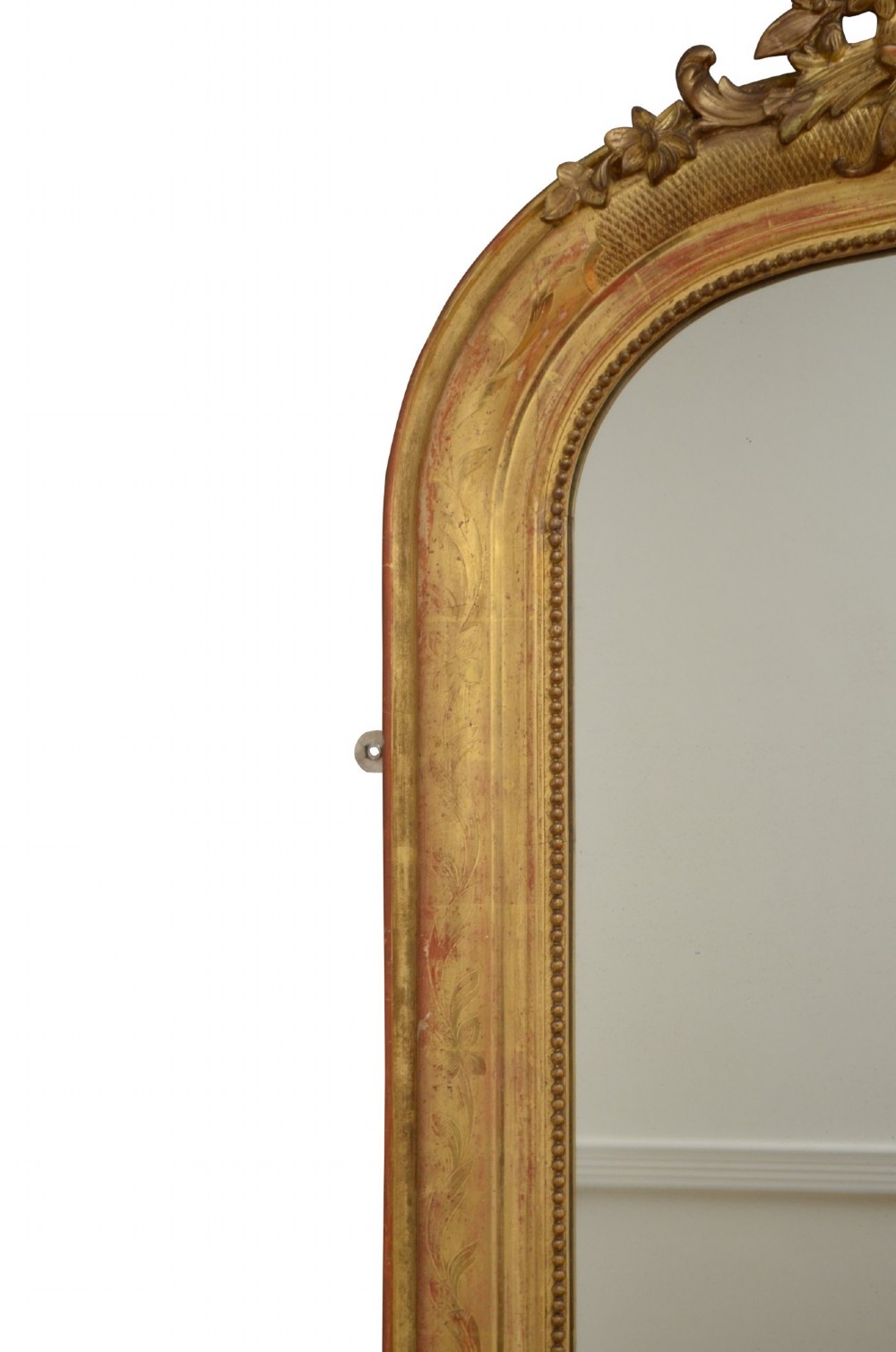 A tall arched giltwood wall mirror featuring an intricate shell cresting at the top and floral carved motifs along the gilded frame. View VI