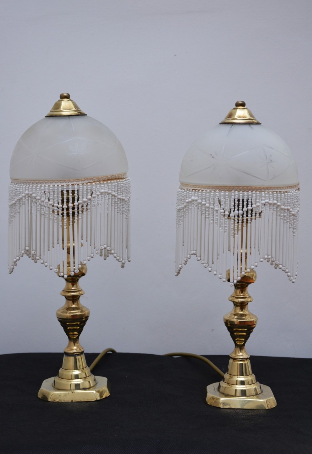 A pair of illuminated Victorian turned brass table lamps featuring etched frosted glass dome shades with beaded fringe hanging around the rim. View VII