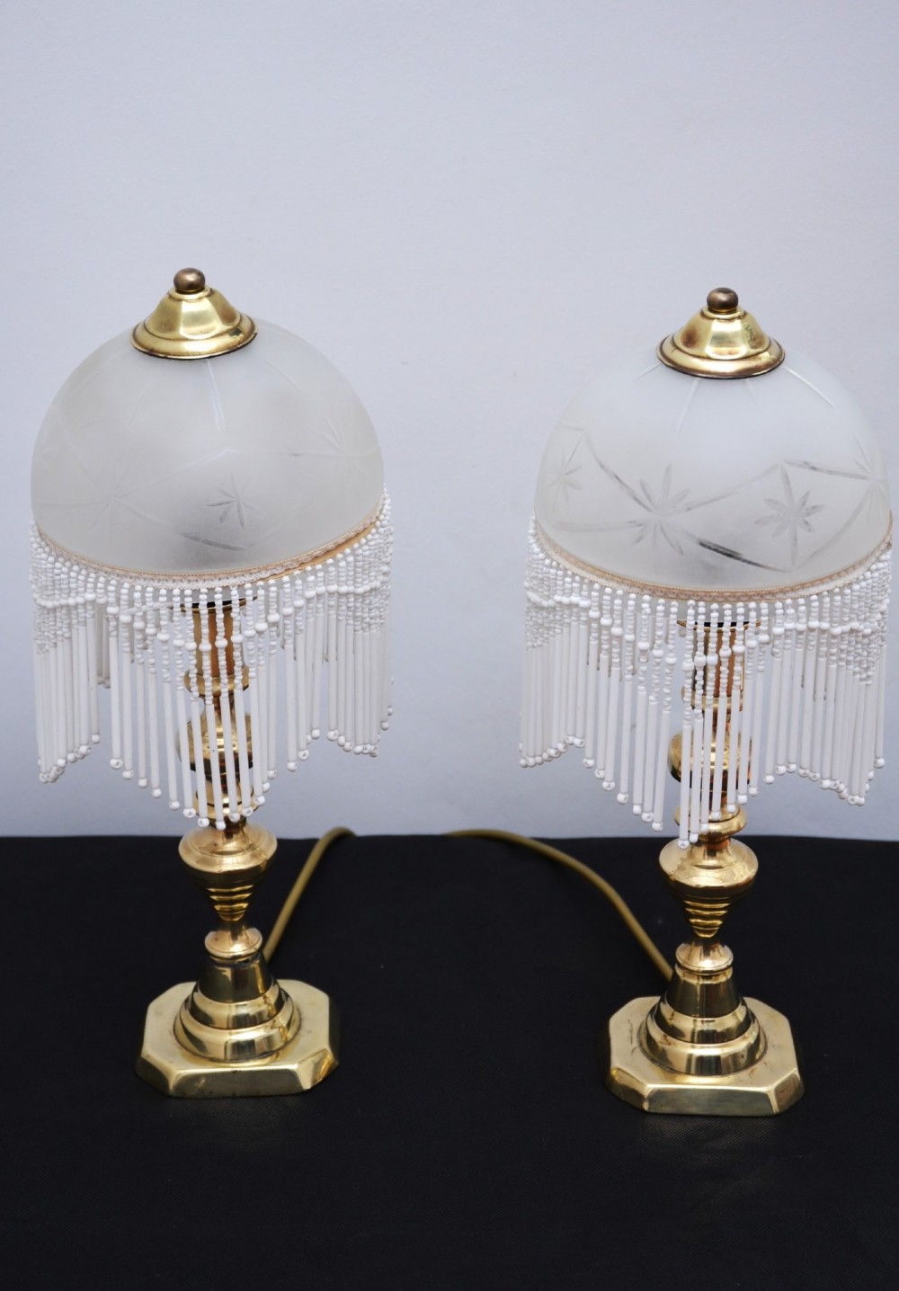 A pair of illuminated Victorian turned brass table lamps featuring etched frosted glass dome shades with beaded fringe hanging around the rim. View VIII