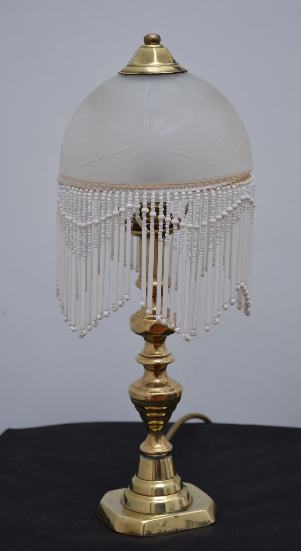 A pair of illuminated Victorian turned brass table lamps featuring etched frosted glass dome shades with beaded fringe hanging around the rim. View IX