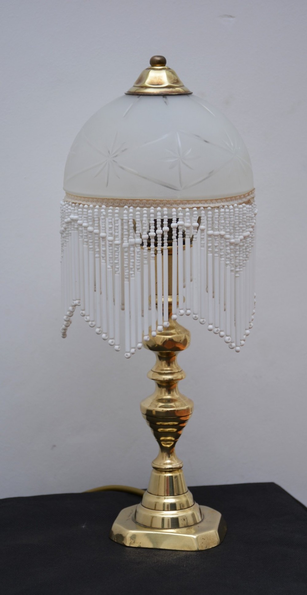A pair of illuminated Victorian turned brass table lamps featuring etched frosted glass dome shades with beaded fringe hanging around the rim. View X