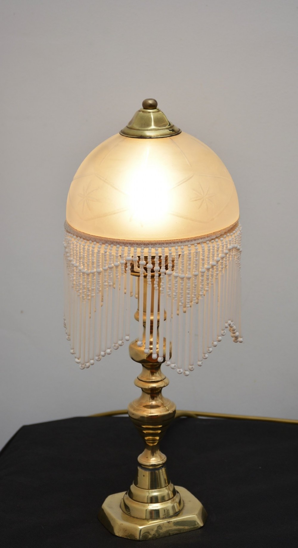A pair of illuminated Victorian turned brass table lamps featuring etched frosted glass dome shades with beaded fringe hanging around the rim. View XI