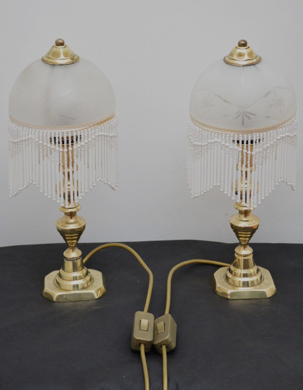 A pair of illuminated Victorian turned brass table lamps featuring etched frosted glass dome shades with beaded fringe hanging around the rim. View XII