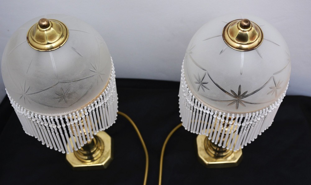 A pair of illuminated Victorian turned brass table lamps featuring etched frosted glass dome shades with beaded fringe hanging around the rim. View XIV