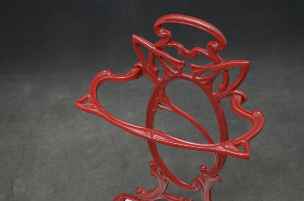 A red painted cast iron Art Nouveau umbrella stand with stylized openwork back plate and white divided base tray. View V