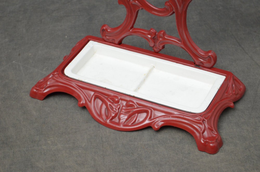 A red painted cast iron Art Nouveau umbrella stand with stylized openwork back plate and white divided base tray. View VI