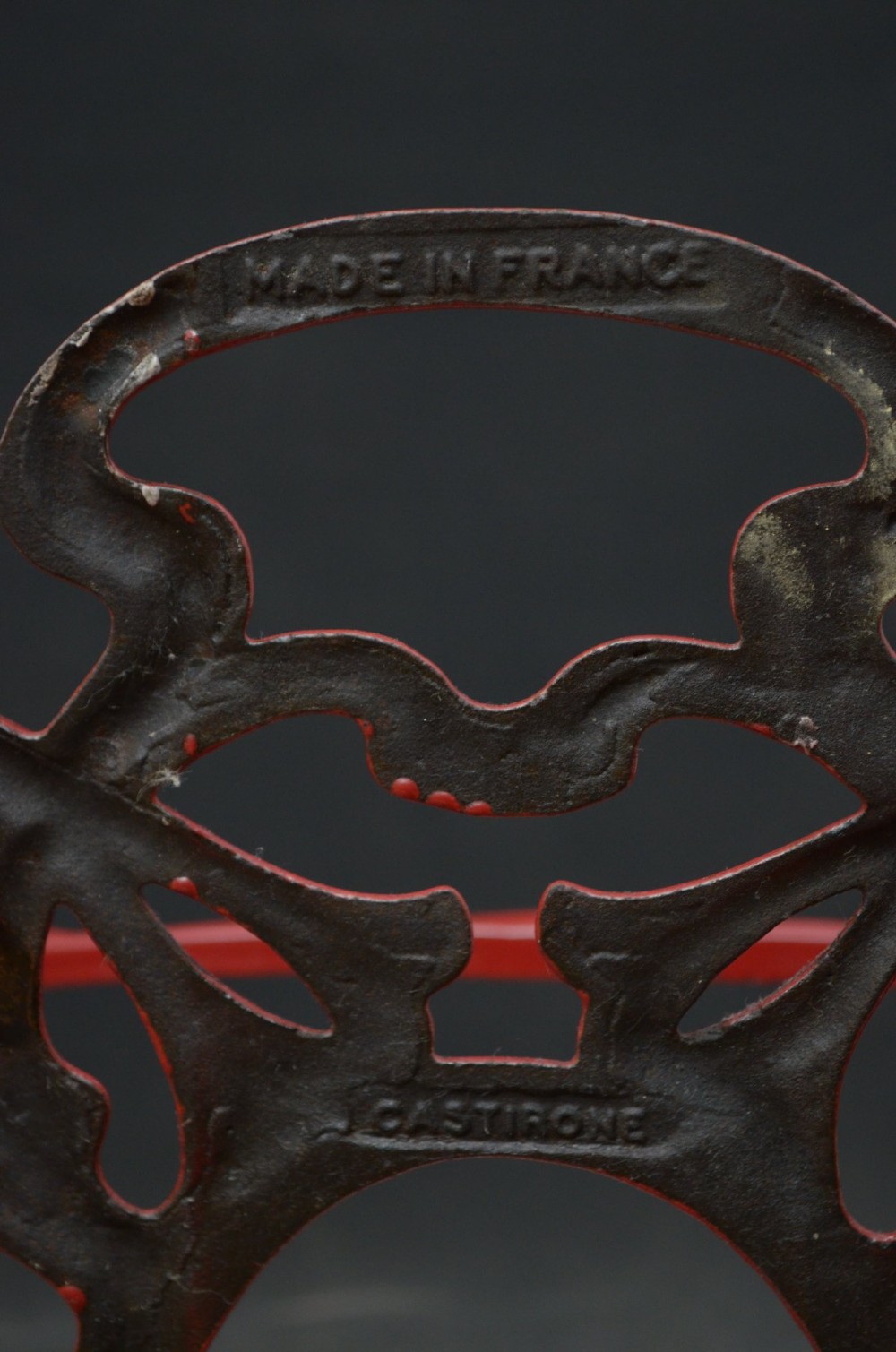 A red painted cast iron Art Nouveau umbrella stand with stylized openwork back plate and white divided base tray. View VII