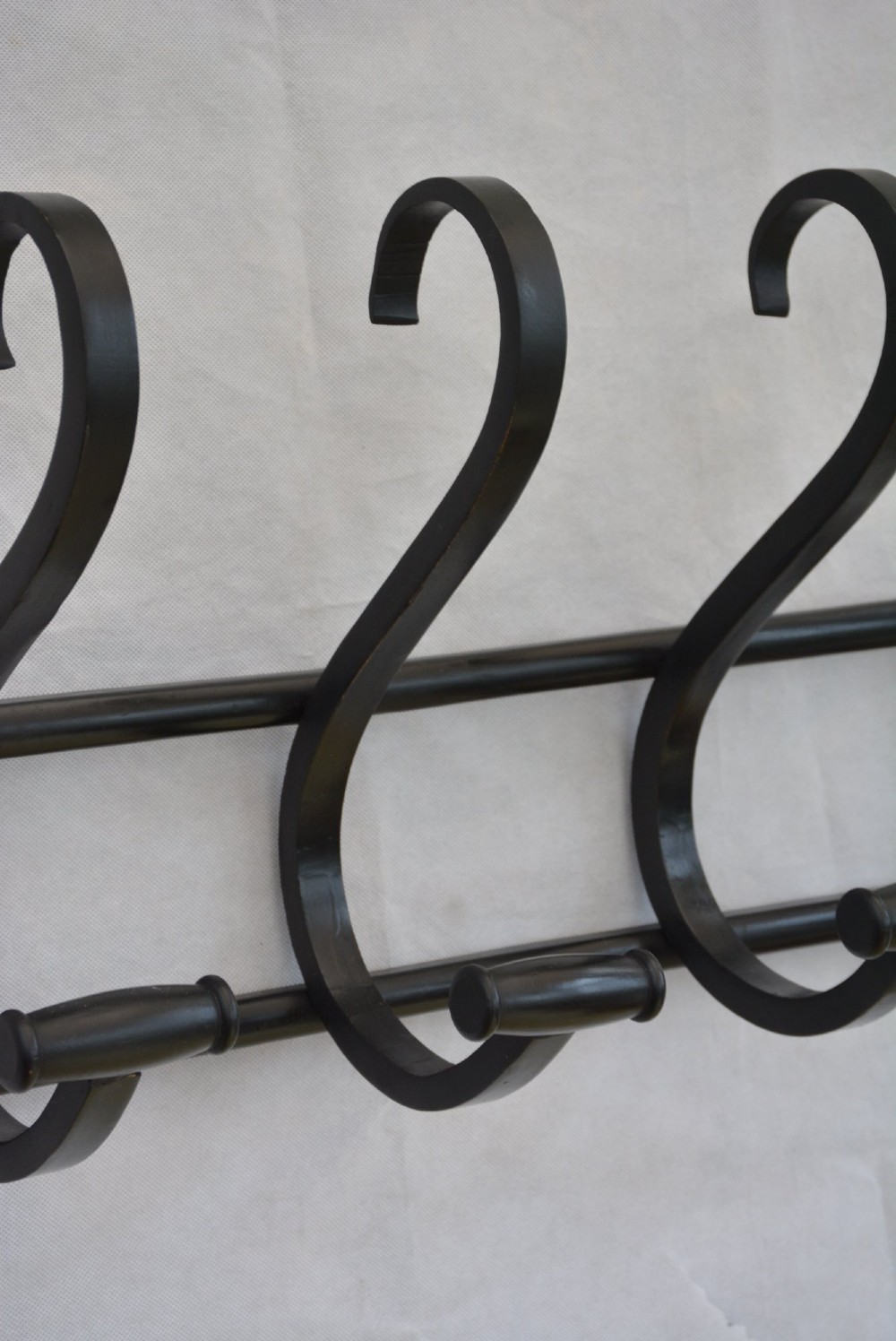 An ebonised bentwood wall-mounted coat rack featuring four large S-curved hooks mounted on a horizontal wooden backing rail. View V