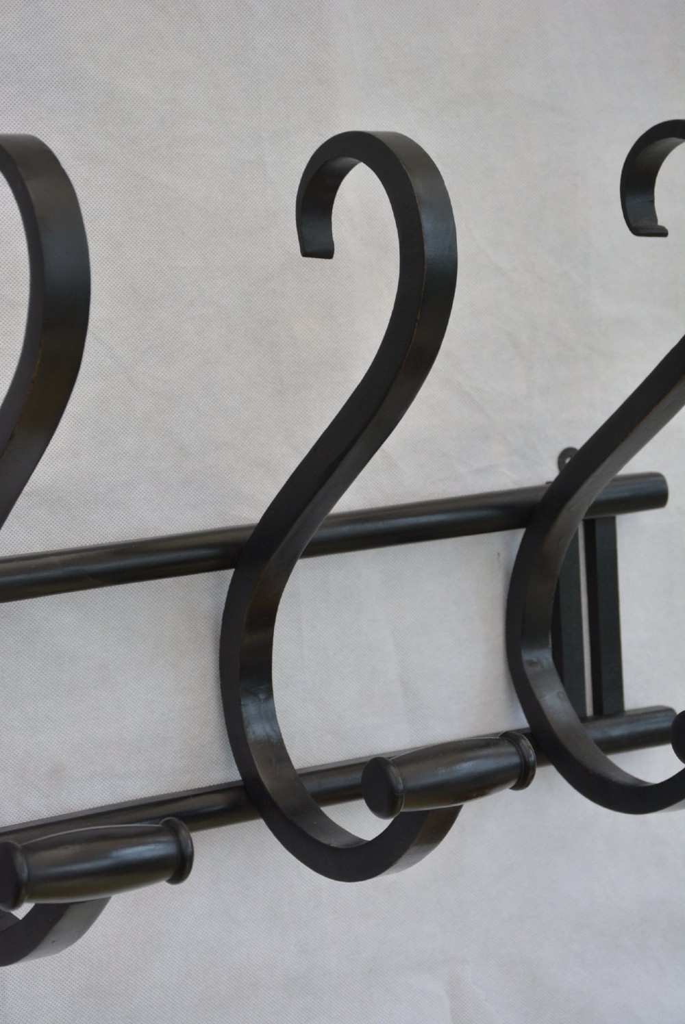 An ebonised bentwood wall-mounted coat rack featuring four large S-curved hooks mounted on a horizontal wooden backing rail. View VI