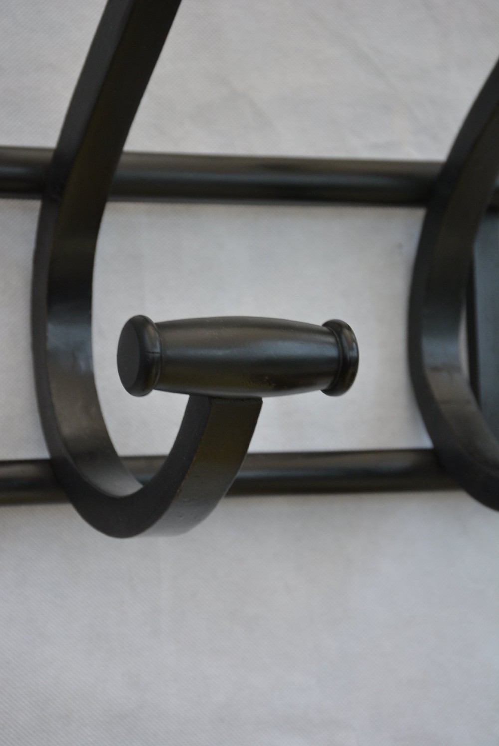 An ebonised bentwood wall-mounted coat rack featuring four large S-curved hooks mounted on a horizontal wooden backing rail. View IX