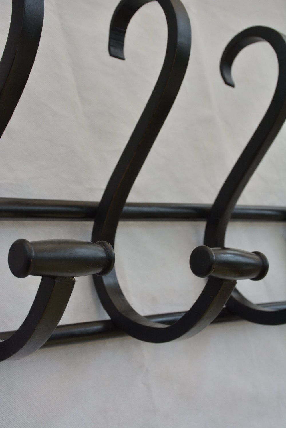 An ebonised bentwood wall-mounted coat rack featuring four large S-curved hooks mounted on a horizontal wooden backing rail. View X