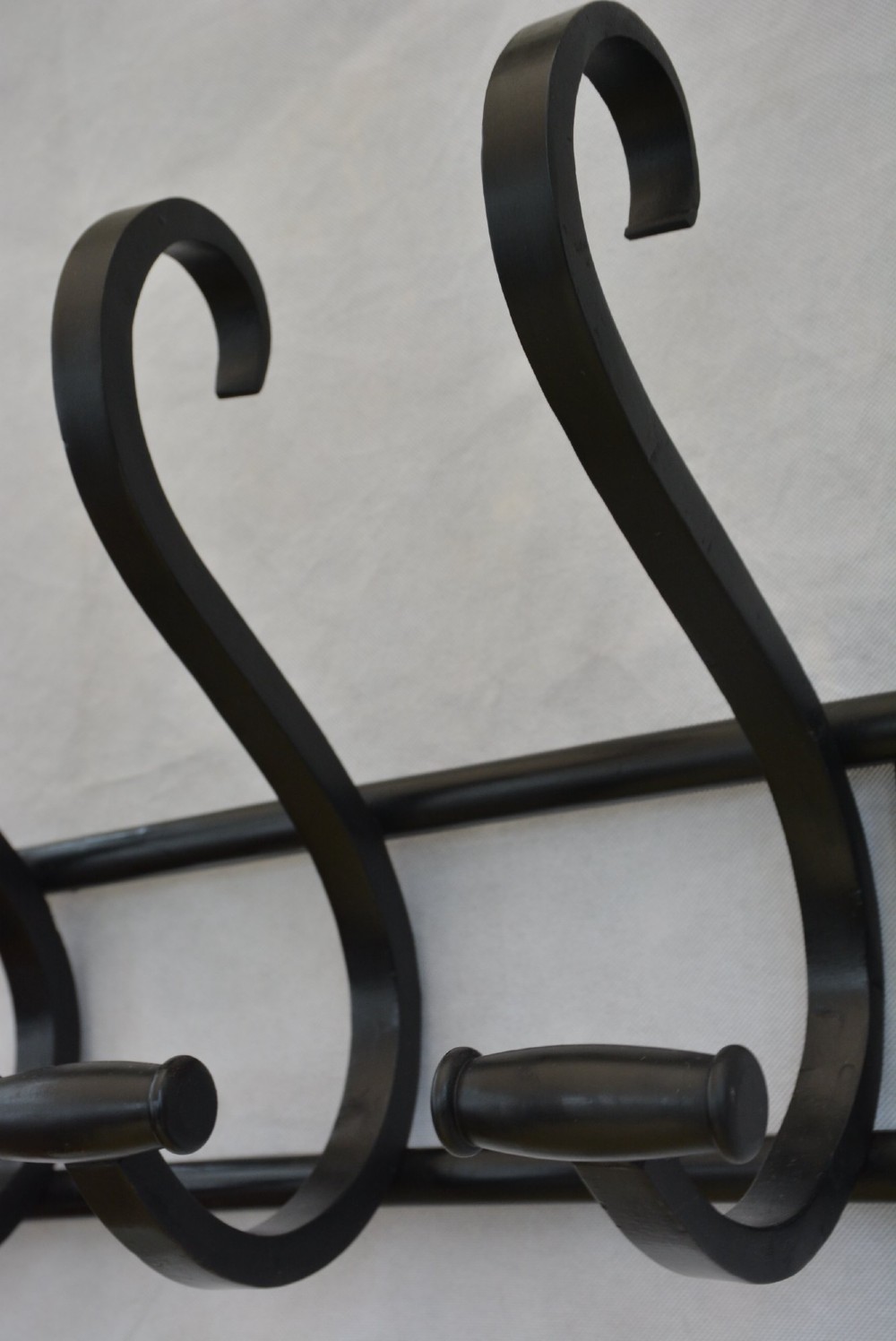 An ebonised bentwood wall-mounted coat rack featuring four large S-curved hooks mounted on a horizontal wooden backing rail. View XII