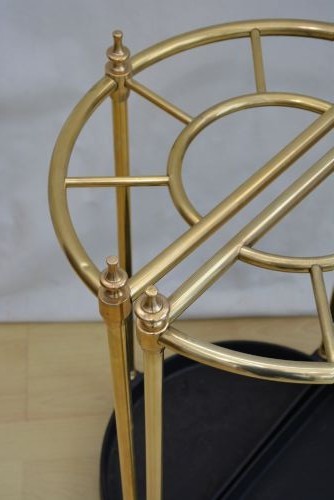 A pair of early 20th-century semi-circular brass umbrella stands with finial posts and black cast iron drip trays, placed back to back. View IV