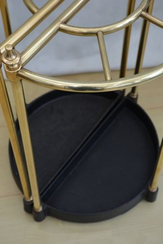 A pair of early 20th-century semi-circular brass umbrella stands with finial posts and black cast iron drip trays, placed back to back. View VI