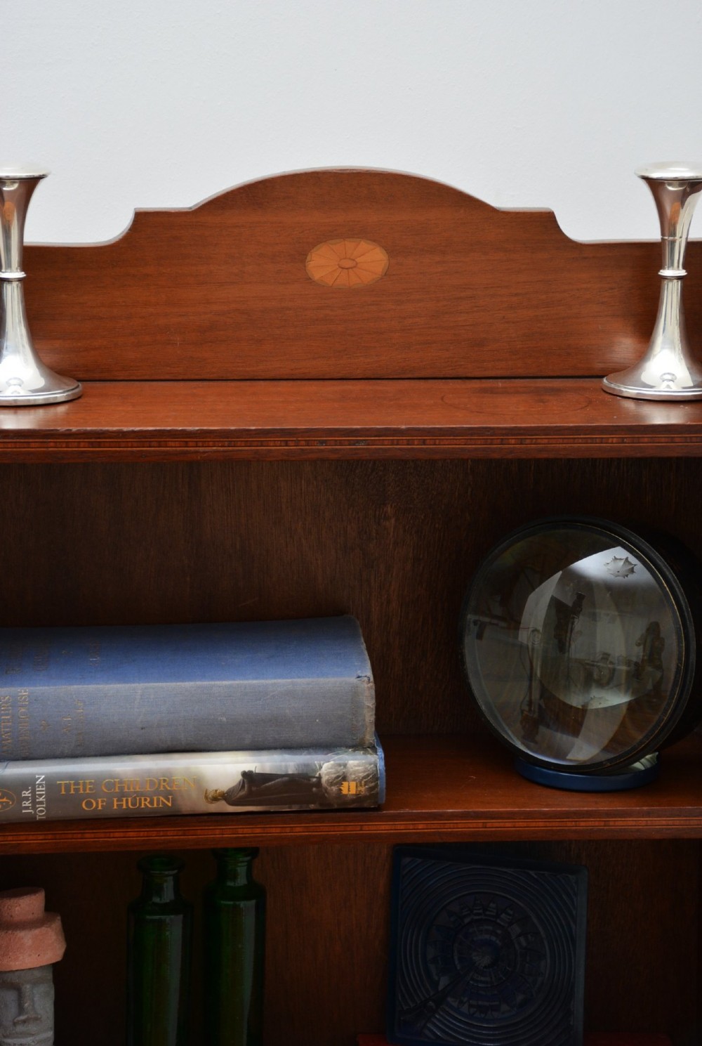 A slim Edwardian mahogany open bookcase featuring four shelves, an inlaid oval motif on the shaped gallery top, and bracket feet. View III