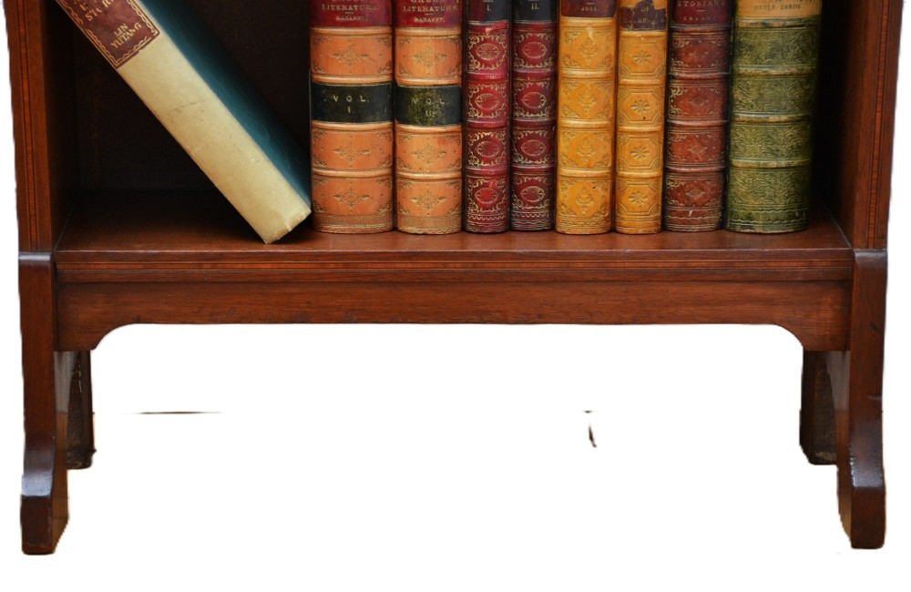 A slim Edwardian mahogany open bookcase featuring four shelves, an inlaid oval motif on the shaped gallery top, and bracket feet. View VIII